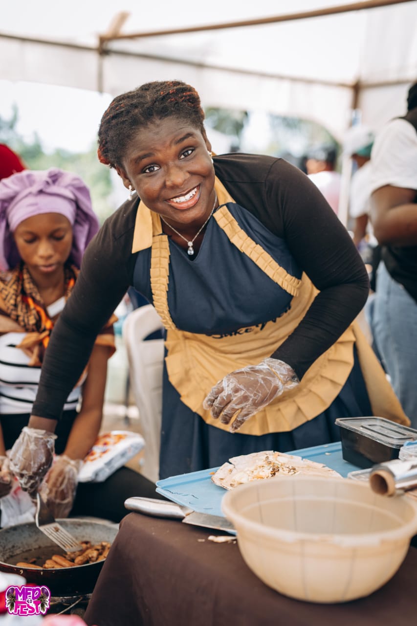A smiling food vendor preparing a plate at MedFest
